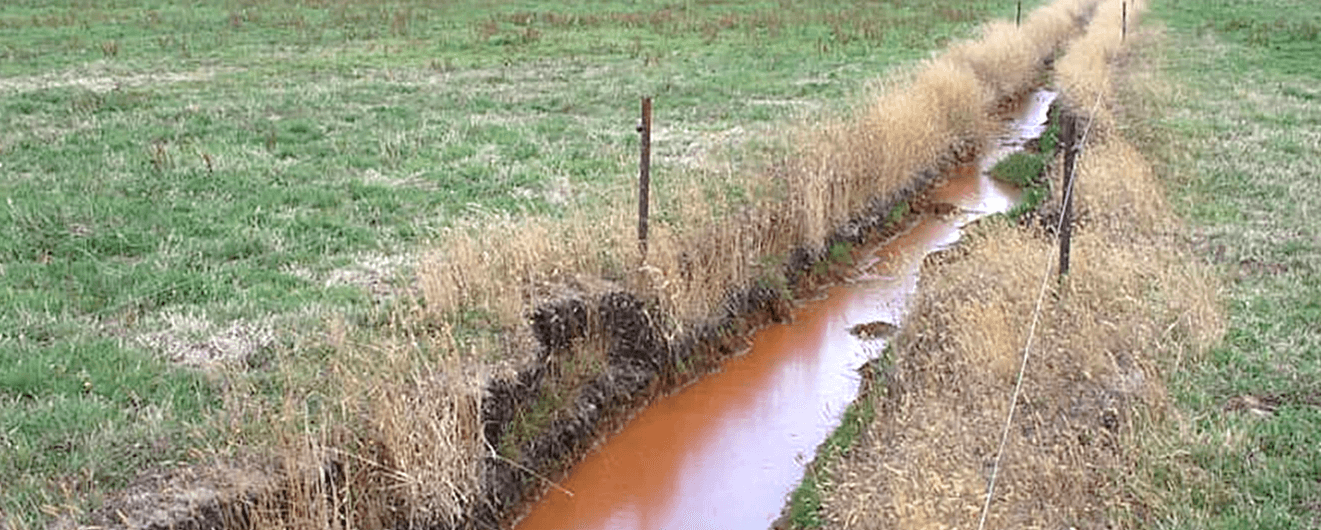 Figure 17. Reddish coloured iron oxide released into surface drains from acid sulfate soil.